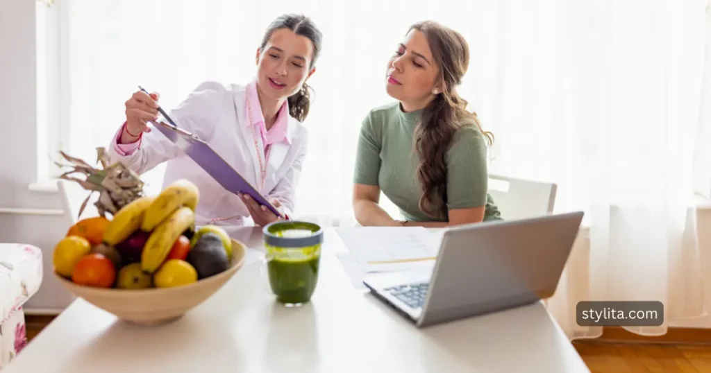 female doctor showing list of nutrients to the health and body composition conscious lady with different fruits placed on the table along with the laptop 