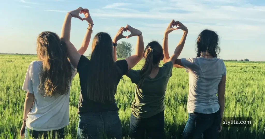 beautiful girls on a nature walk to green fields making hand hearts with each others hands