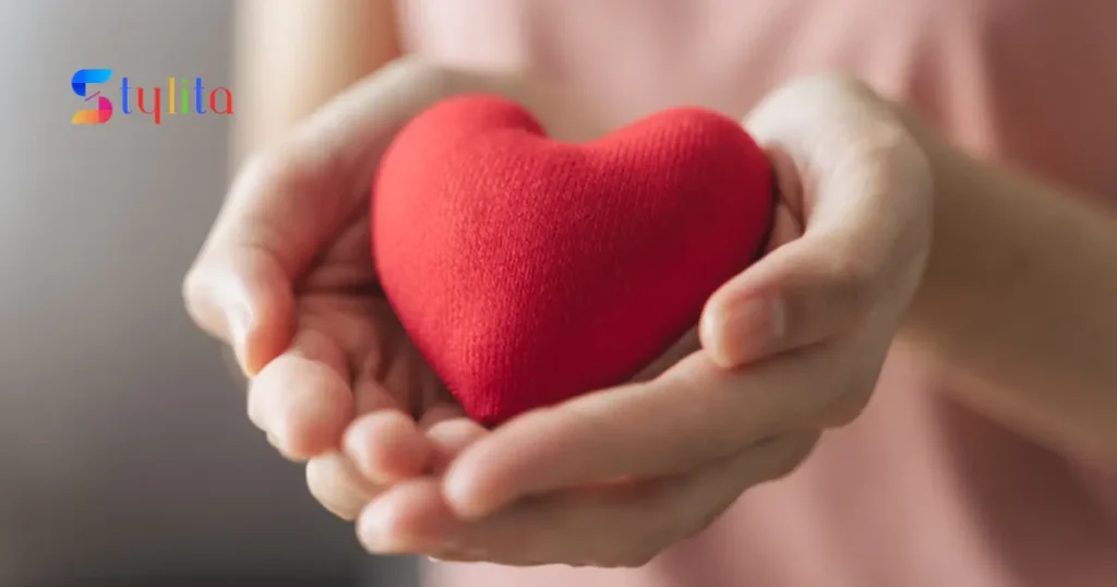 girl's hand holding a red heart made of stuffed cloth